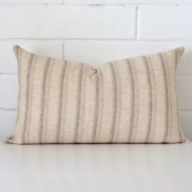 Striped cushion positioned in front of a brick wall. It has rectangle dimensions and is made from a designer material.