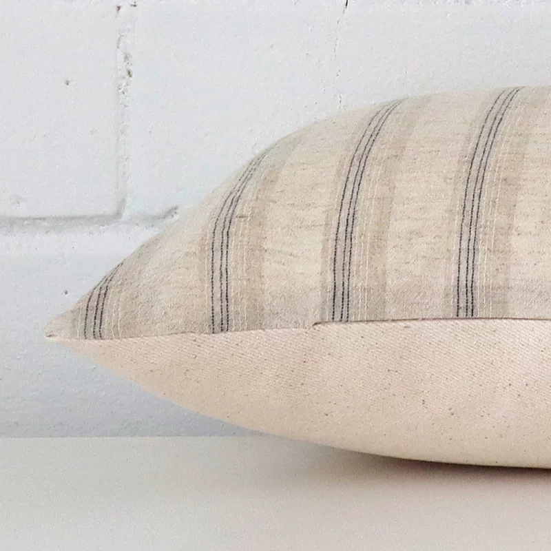 A rectangle designer cushion positioned flat to show its seams. The striped design are visible as is the seam between the panels.