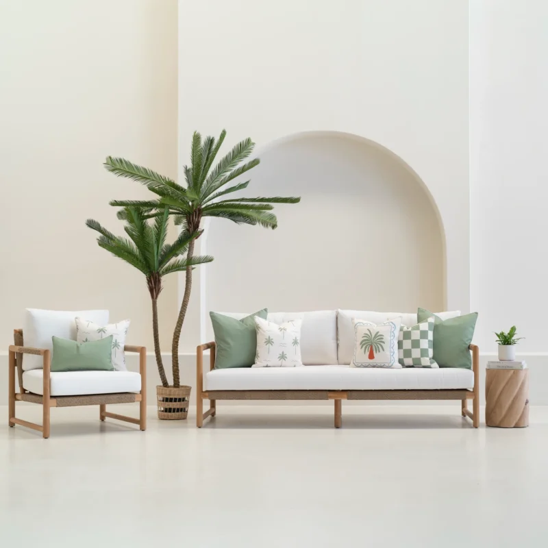 Green cushions styled on outdoor sofa and chair with tropical accents.