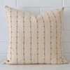 Striped cushion leans elegantly against a brick wall. It has been crafted from a high quality designer material and has a large size.