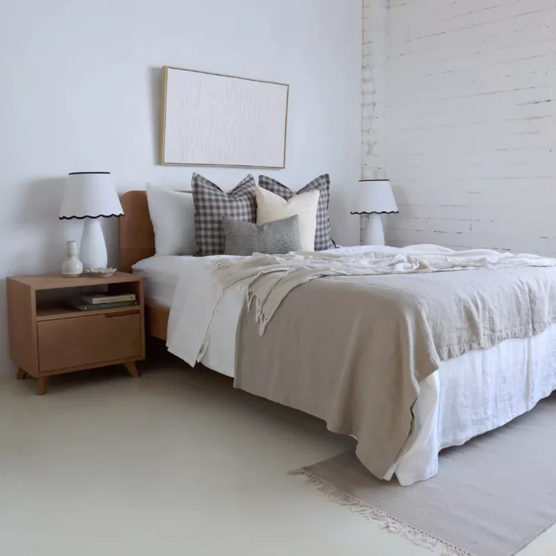 An airy white bedroom with 4 designer cushions from the Jude set sitting on a wooden bed.