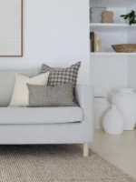 A set of 5 designer sofa cushions are arranged nicely on a light grey sofa in a living room.