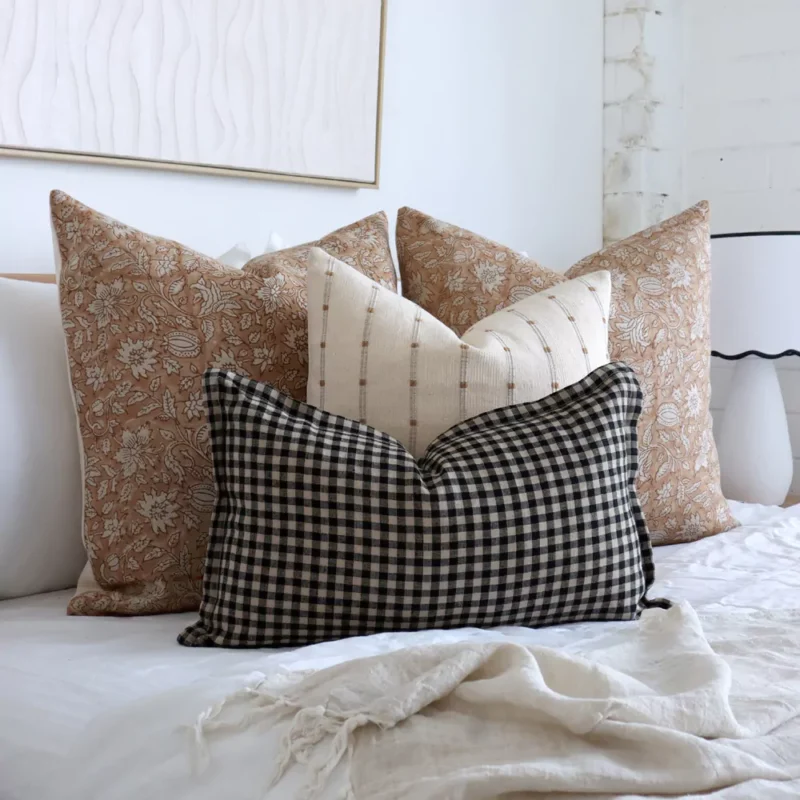 An image showing 4 designer bed cushions in a white-themed bedroom.