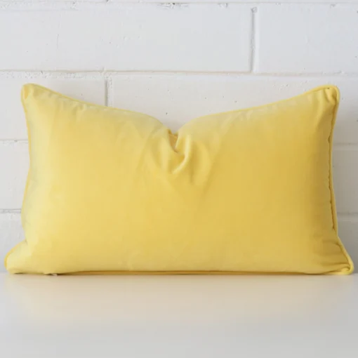 A hero shot of a rectangle cushion cover. It is made from a deluxe velvet fabric and features a lemon yellow colour.