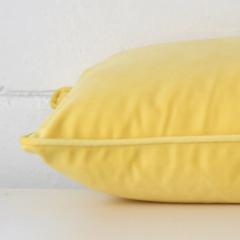 The seams of this velvet rectangle cushion cover in lemon yellow are shown.