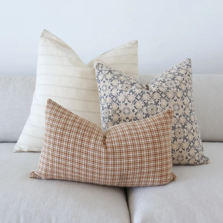 3 designer couch cushions are neatly arranged on a gray sofa in perfect coordination.