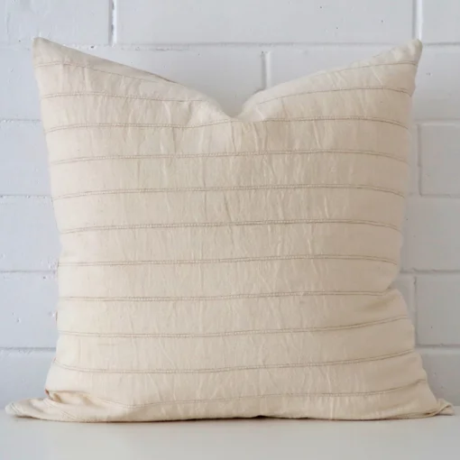 A pretty striped designer cushion cover is shown against a brick wall. It has a large size.