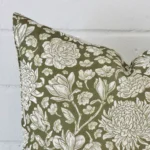 Close up of a linen square cushion in green colour. The quality of its floral design is shown in fine detail.