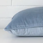 A blue cushion positioned on its back panel. The shot shows a lateral view of the velvet fabric and its large size.