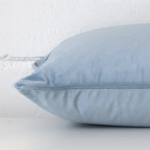 Horizontal edge of rectangle cushion cover is shown. The velvet fabric and light blue tone can be seen from this side view.