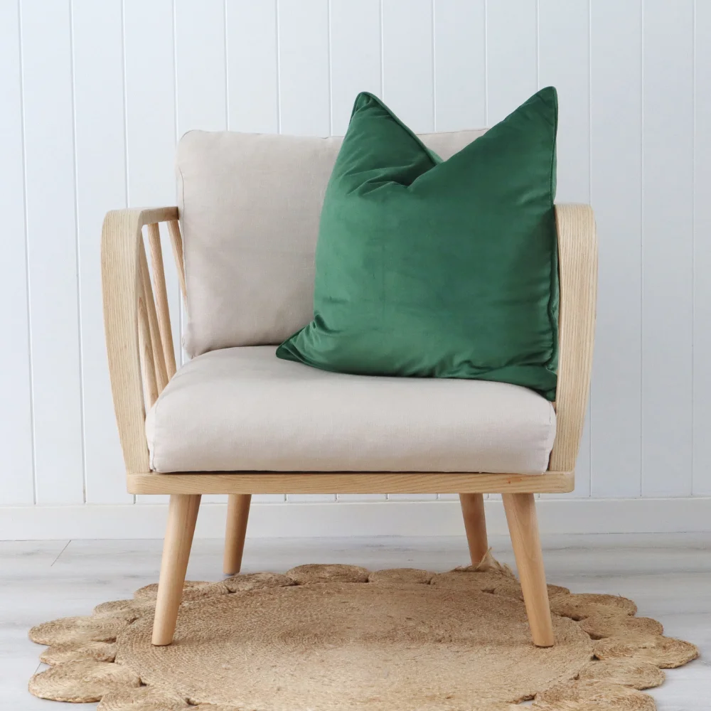 A light coloured armchair with a green cushion.