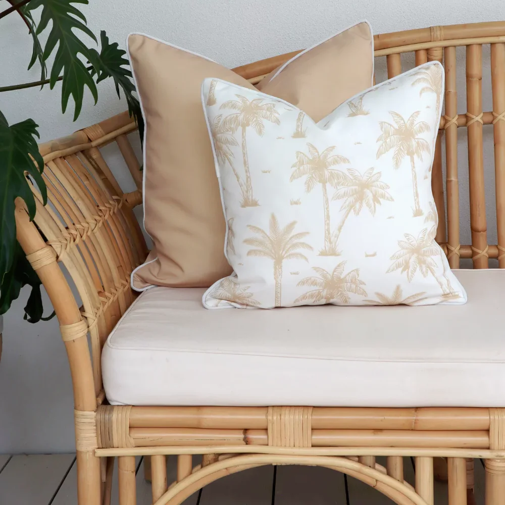 A light wicker outdoor chair is shown with some beige outdoor cushions on it.