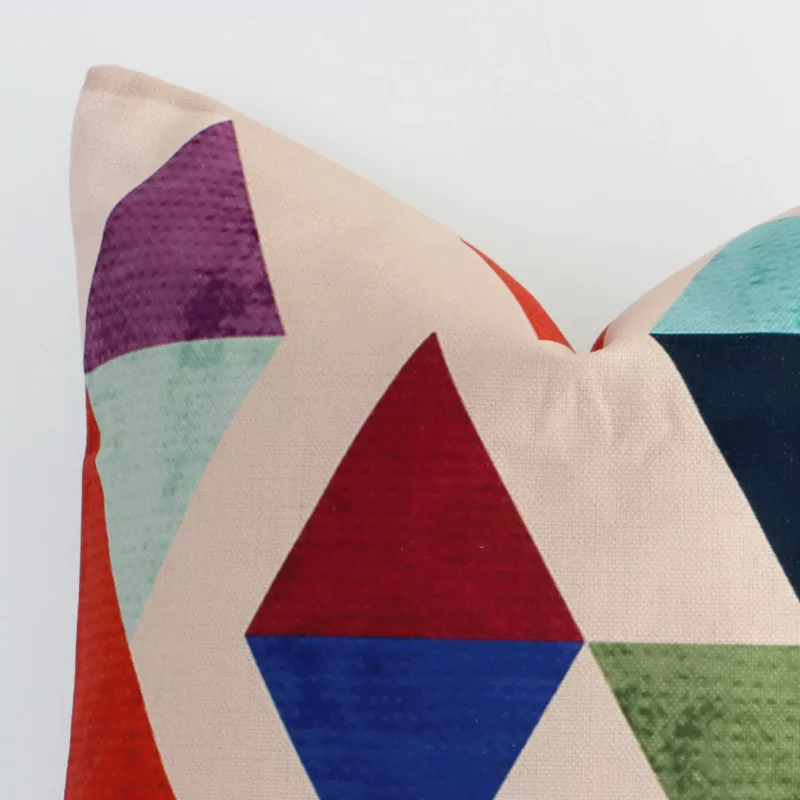 Corner section image showing features of square colourful cushion that has a geometric motif on its linen fabric.