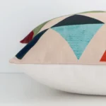 A sideways perspective of this geometric linen cushion. The positioning shows the border of the square shape and its mix of colourful prints.