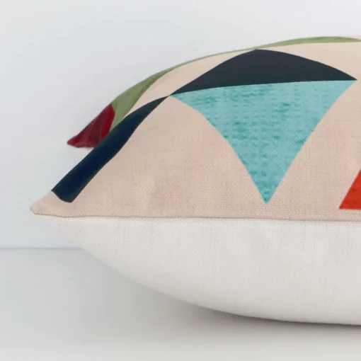 A sideways perspective of this geometric linen cushion. The positioning shows the border of the square shape and its mix of colourful prints.