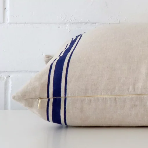 rectangle striped cushion in blue colour laying flat. The viewpoint highlights the seams of the linen fabric.