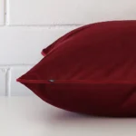 A side shot of a velvet cushion cover. The angle shows the edge of the shape and the maroon tone.