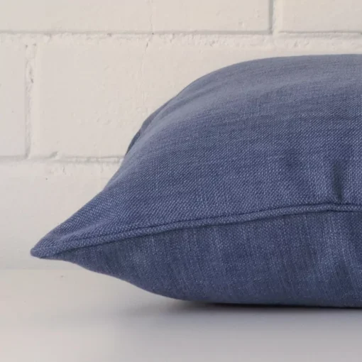 A square royal blue cushion cover laying flat. This viewpoint highlights the linen fabric from a side position.