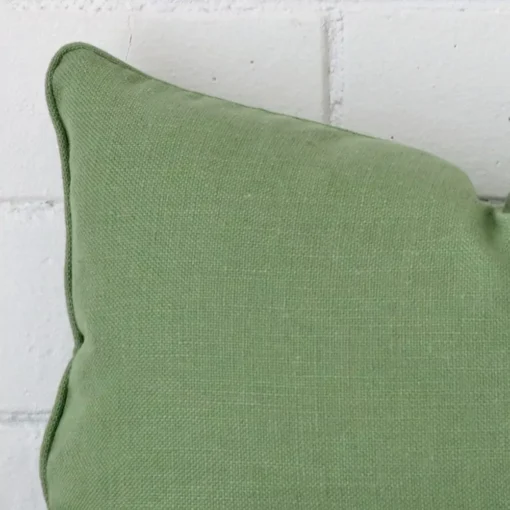A sage green linen cushion cover’s corner is shown in more detail.