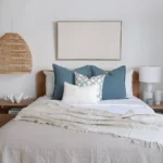 Four bed cushions are neatly arranged on a bed in a white bedroom.