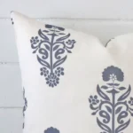 A light blue linen cushion cover’s corner is shown in more detail. It is possible to see the edge of the square design and patterned decorative finish in much more detail.