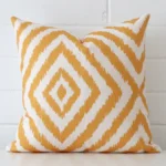A square geometric cushion in rests against a white wall. The linen material appears to be of exceptional quality.