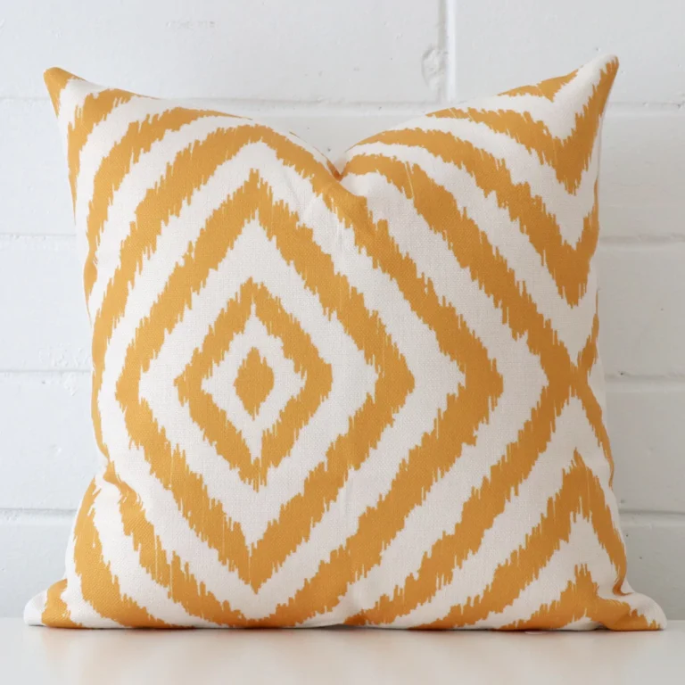 A square geometric cushion in rests against a white wall. The linen material appears to be of exceptional quality.