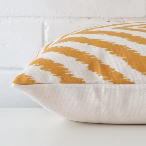 A linen cushion cover shown laying on its side. The geometric design and its square size are shown side on.