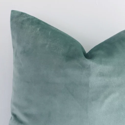 Close range image of mint solid-coloured cushion. The square shape and velvet material can be seen in detail.