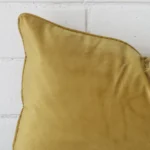 A close up shot showing the top left side of this rectangle velvet cushion cover. The mustard tone is magnified.