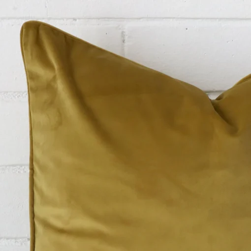 Zoomed photo of the top left corner of this mustard cushion cover. The image clearly shows the velvet material and large dimensions.