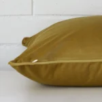 A large velvet cushion positioned flat to show its seams. The mustard colour is shown up close.