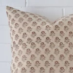 A zoomed in photo of the corner of a floral cushion that has designer fabric and a large size.