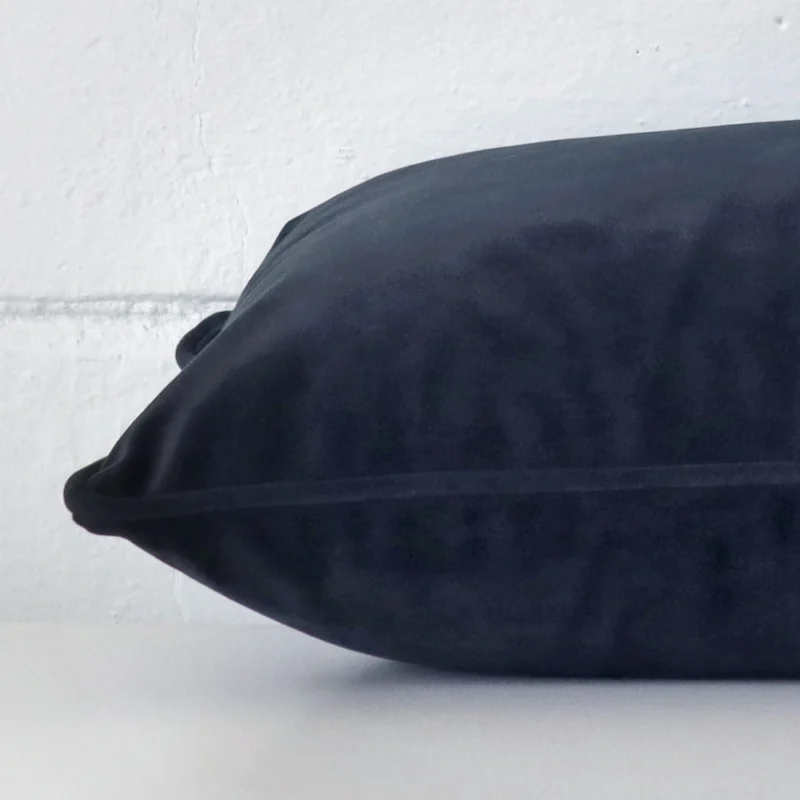 Rectangle cushion in navy colour laying flat. The viewpoint highlights the seams of the velvet fabric.