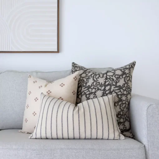 Three couch cushions are sitting in the corner of a light grey sofa.