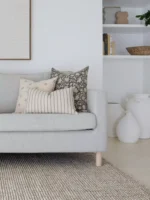 A grey sofa is adorned with the three of elegant Nellie sofa cushions, a set of five designer cushions.