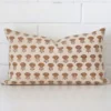 Here a designer cushion is shown styled against a white wall. It has a rectangle design and features a floral style.
