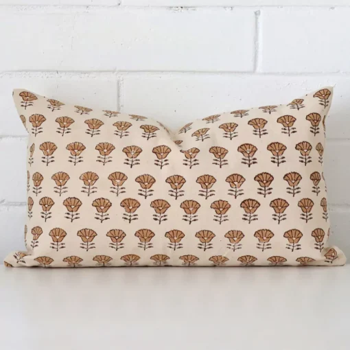 Here a designer cushion is shown styled against a white wall. It has a rectangle design and features a floral style.