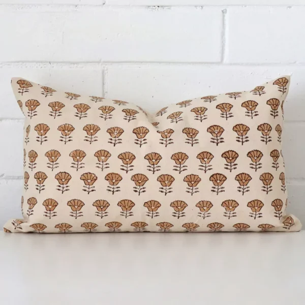 Here a designer cushion is shown styled against a white wall. It has a rectangle design and features a floral style.