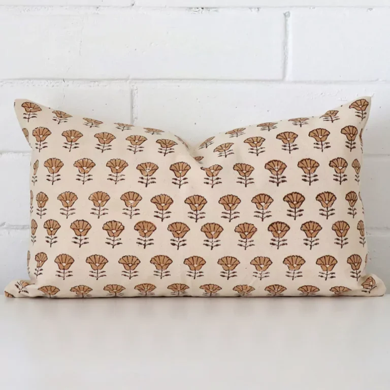 Here a designer cushion is shown styled against a white wall. It has a rectangle design and features a floral style.