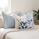 Trio of cushions with sky blue linen, a button-detail cushion, and a coral print, on a couch.