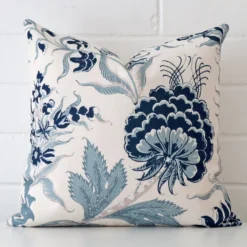 A pretty floral linen cushion cover is shown against a brick wall. It features a square shape.