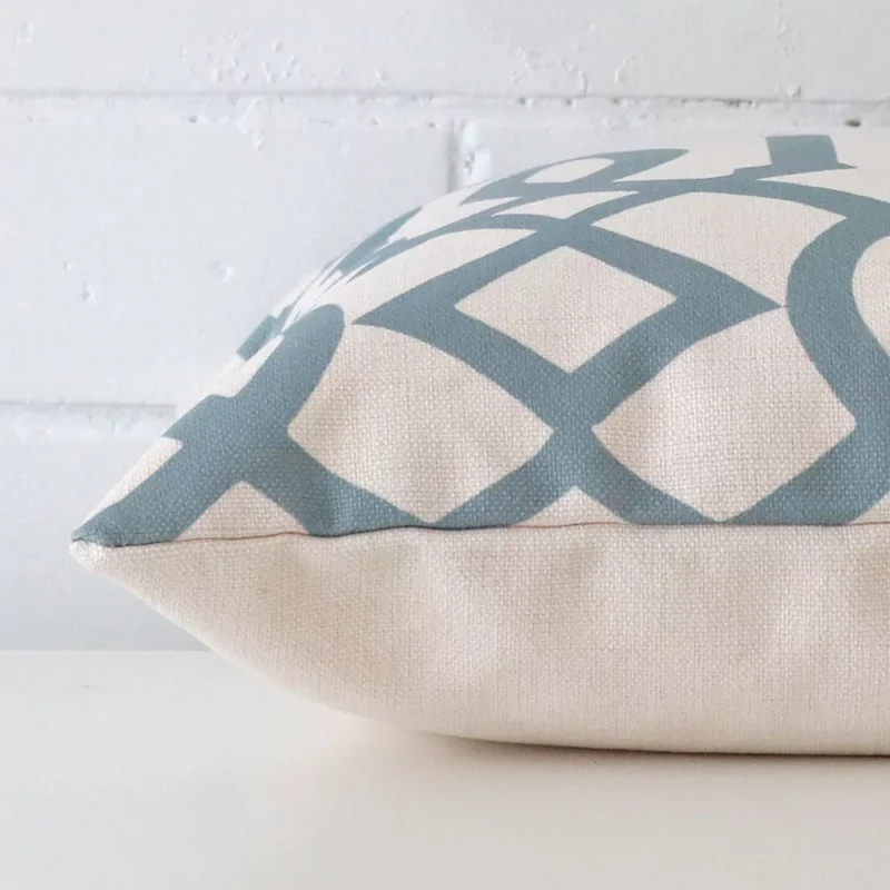 Lateral angle image of a linen square cushion. The patterned design is highlighted along its seams.