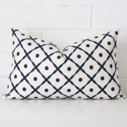 Cushion positioned in front of a brick wall. It has rectangle dimensions and is made from a linen material.