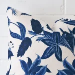 A zoomed in photo of the corner of a floral cushion that has linen fabric and a square size.