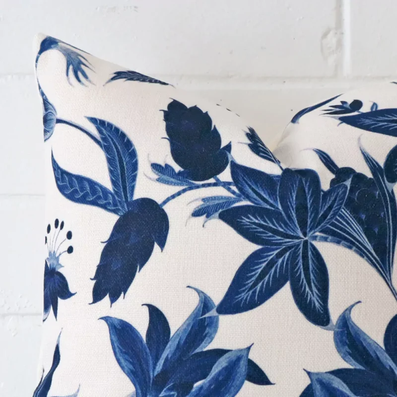 A zoomed in photo of the corner of a floral cushion that has linen fabric and a square size.
