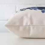 Horizontal edge of floral square cushion cover is shown. The linen fabric can be seen from this side view.