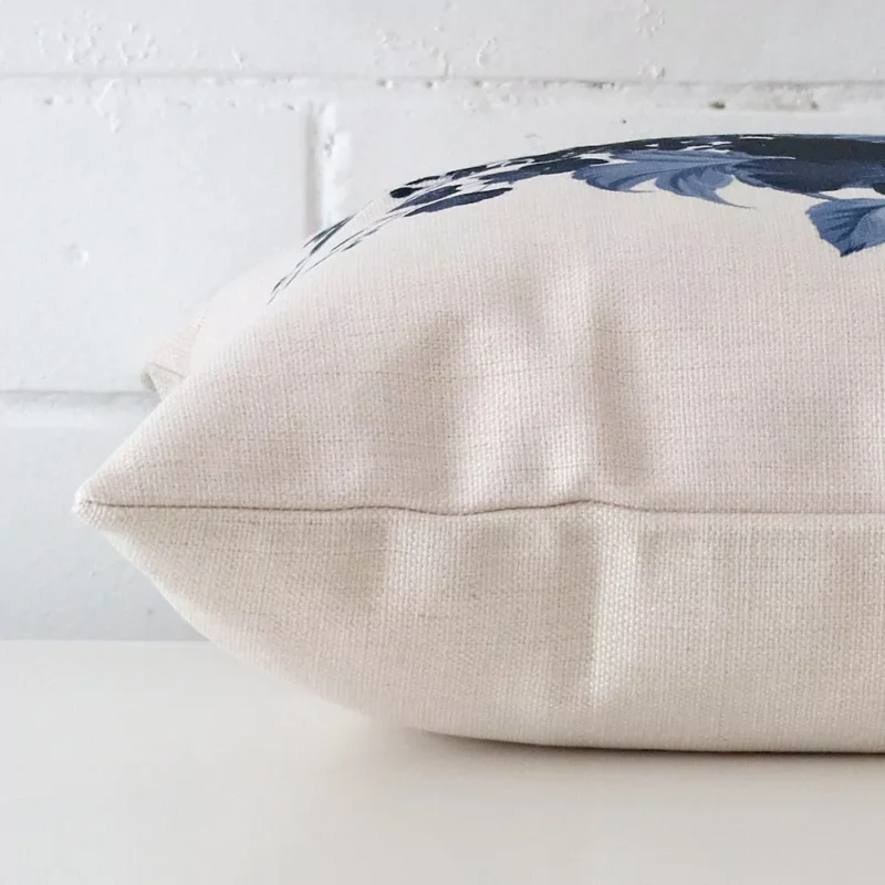 Horizontal edge of floral square cushion cover is shown. The linen fabric can be seen from this side view.