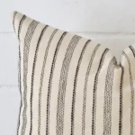 A zoomed view of this designer cushion’s corner that shows a magnified view of its striped design and its large size.