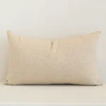Linen rectangle cushion with a solid-coloured design in an upright position against a wall. It is natural in colour.